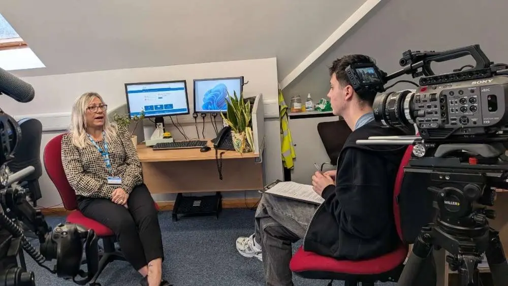 A student off camera interviewing on the receptionists for the documentary