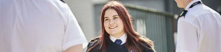 A female officer cadet in uniform talking to two male officer cadets