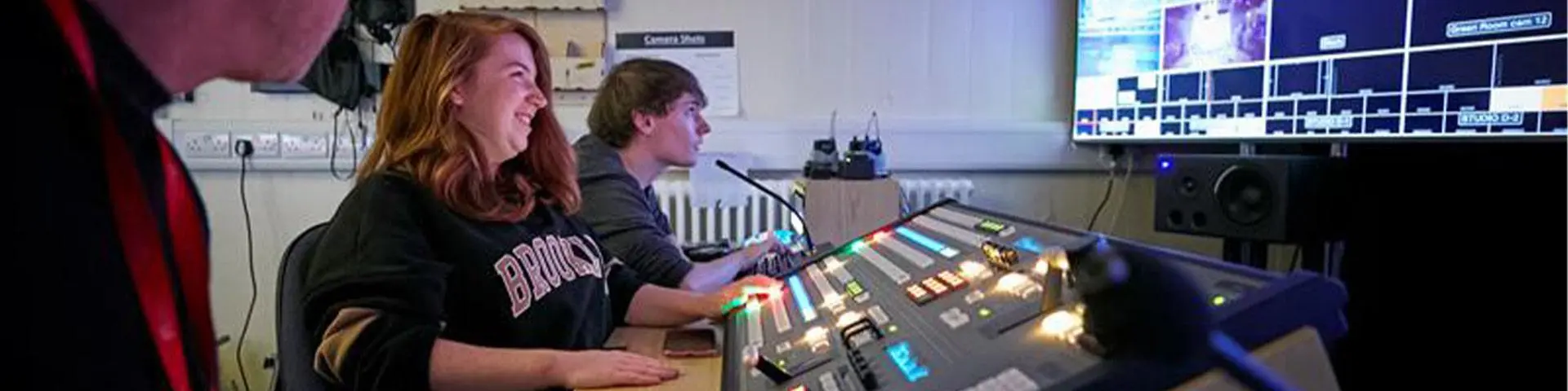 Two students at at a mixing desk in a music studio. 