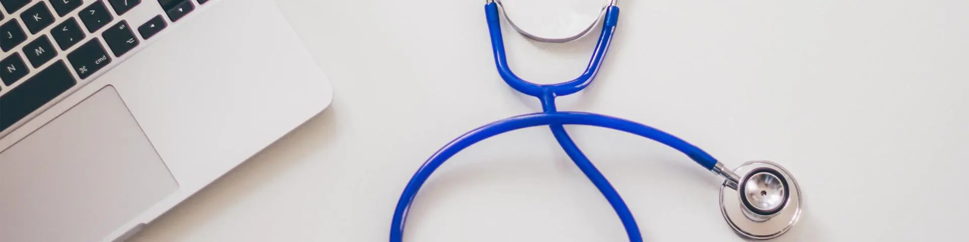 A stethoscope next to a laptop.