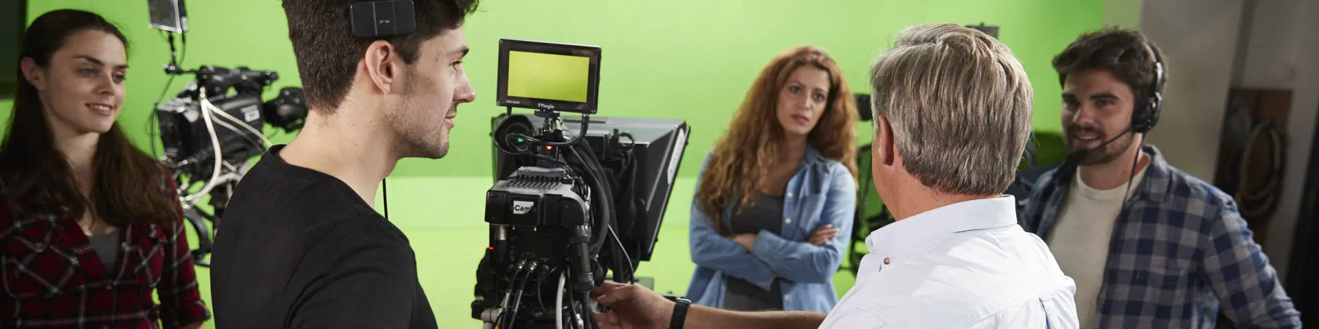 A group of in a studio, standing against a green screen.