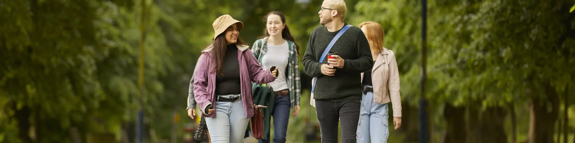 A group of four students walking through the park