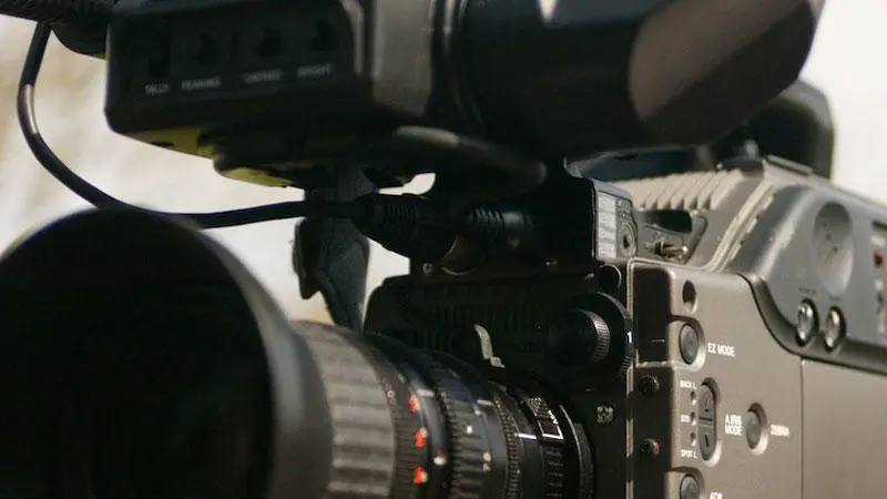 A film camera in focus with a blurry woodland behind