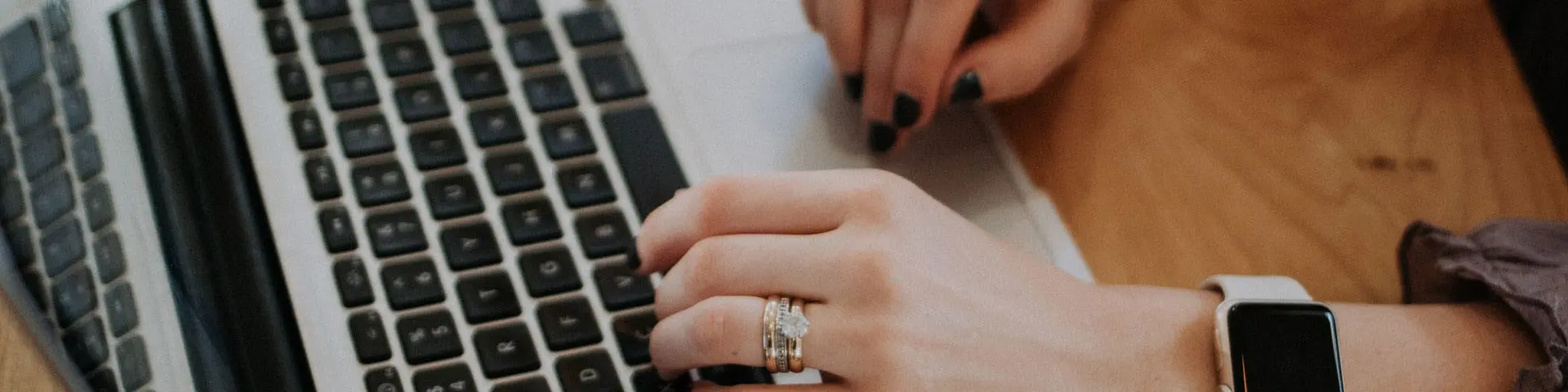 A person wearing an Apple Watch typing on a laptop