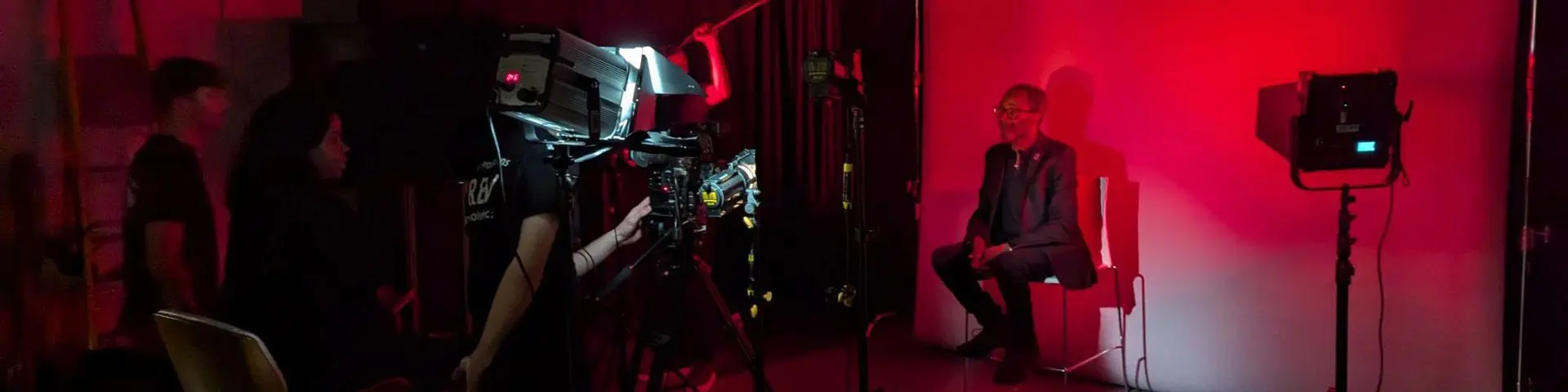 Students filming a city resident in front of a big screen.