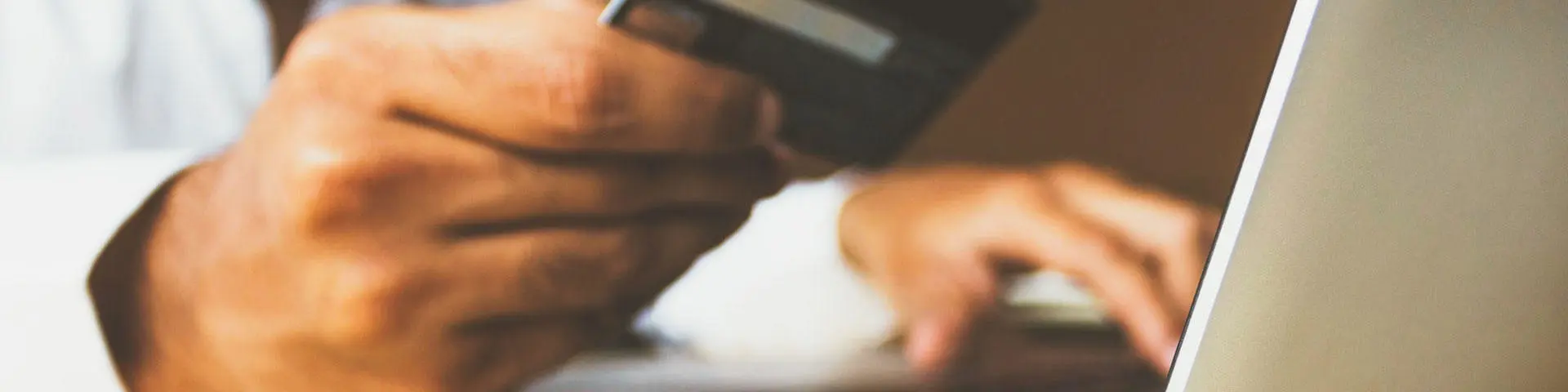 A man holding a debit card at a laptop.