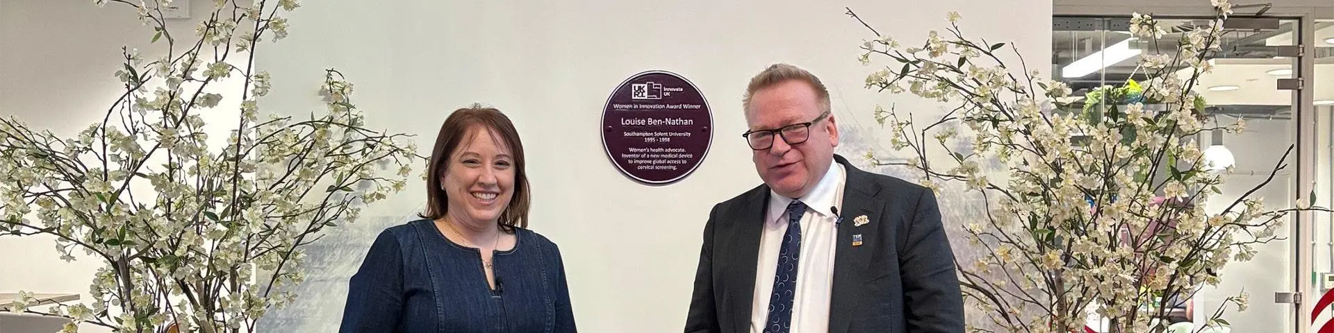 Louise Ben-Nathan with Vice-Chancellor, Professor James Knowles in front of a purple plaque in The Spark.