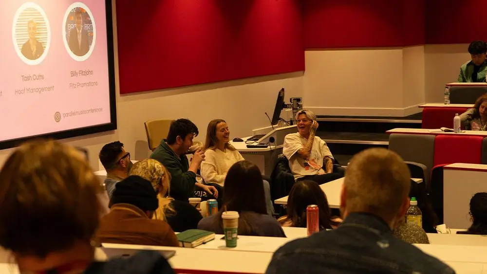 A panel talking in front of an audience in the Palmerston Lecture Theatre at Southampton Solent University.