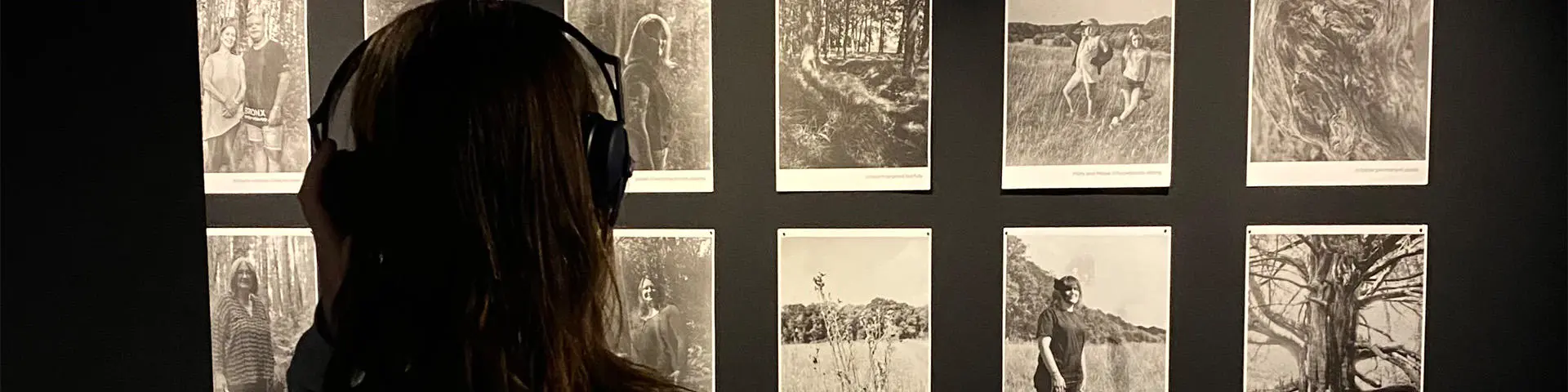 A woman viewing a selection of images displayed at an exhibition.