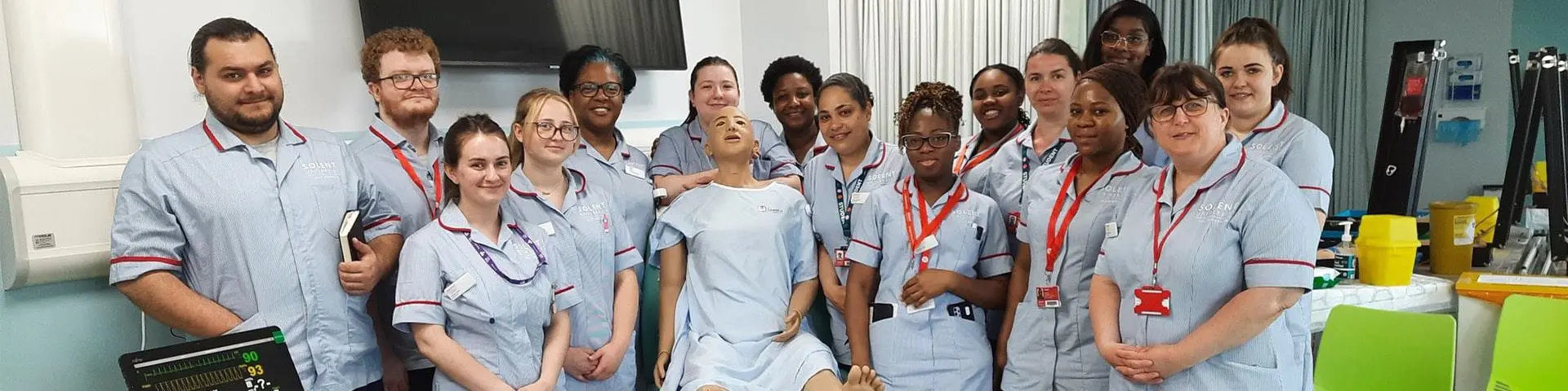 Nursing students stood together with a mannequin in a simulated hosipital ward.