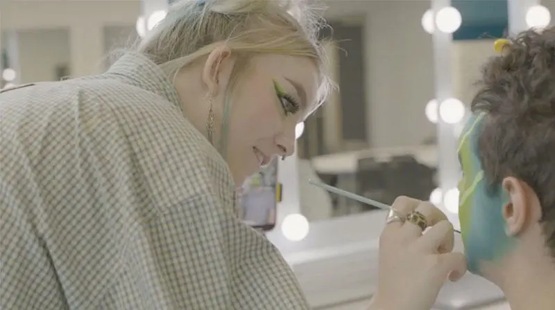 Still of Ella applying make-up to her model