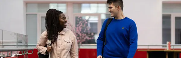 A male and female student looking at each other and smiling