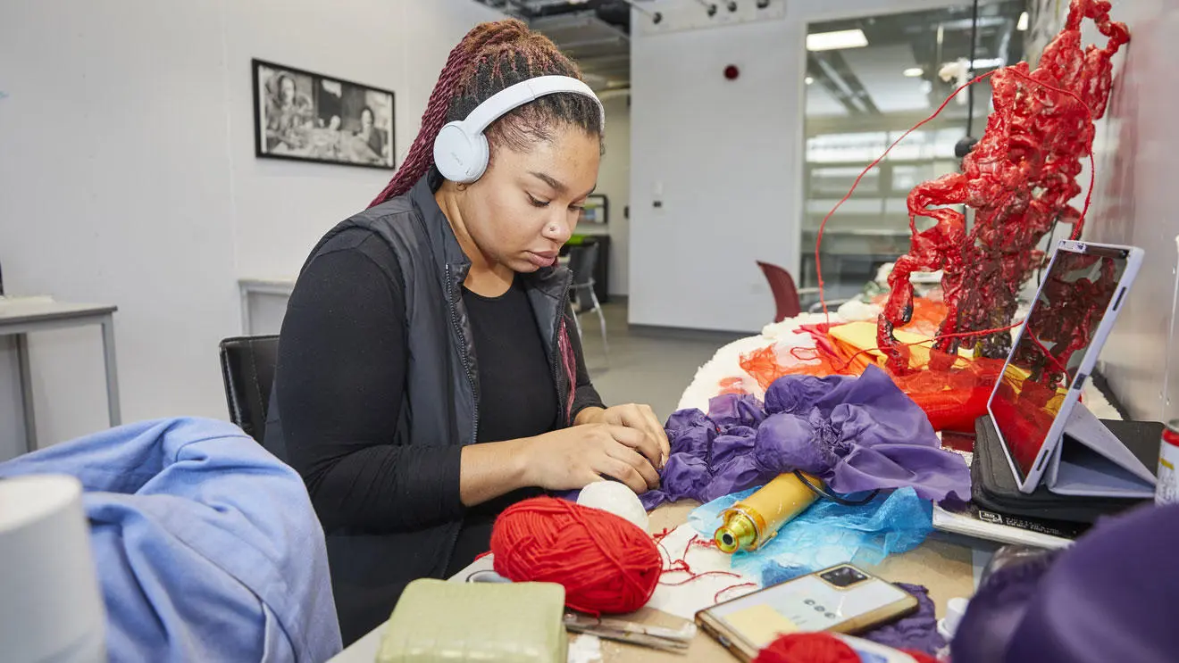 A student making artwork out of wool