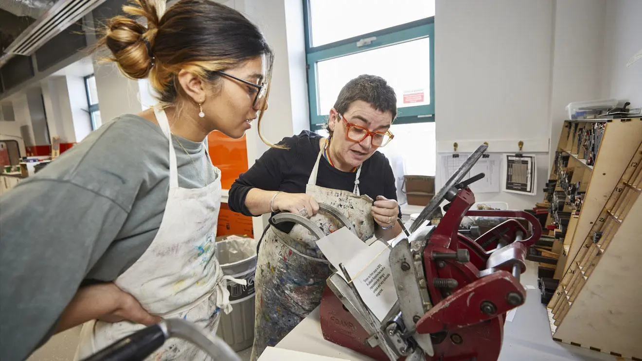 A design student with a technician at the print press