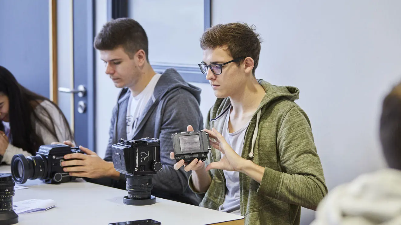 Students taking apart cameras