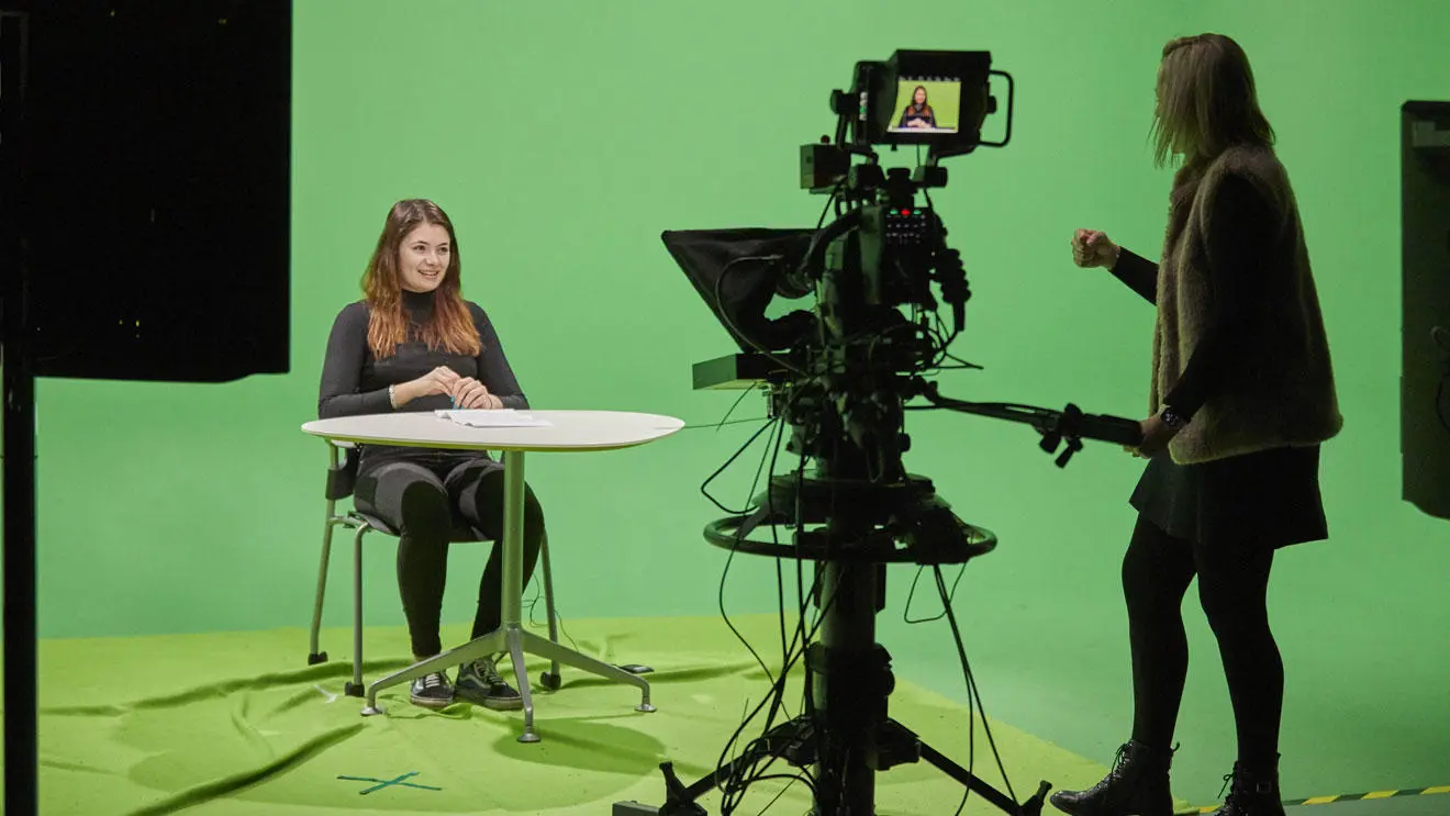 Students sitting in front of a green screen