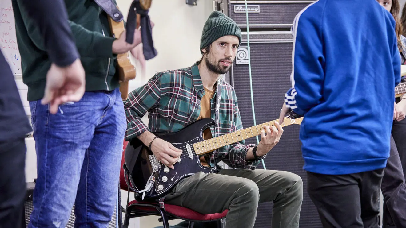 A music performance student holding a guitar