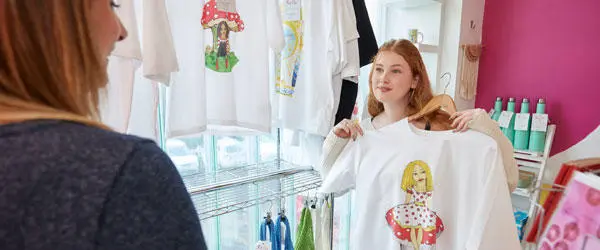 A student working in Re:So showing a t-shirt to a customer