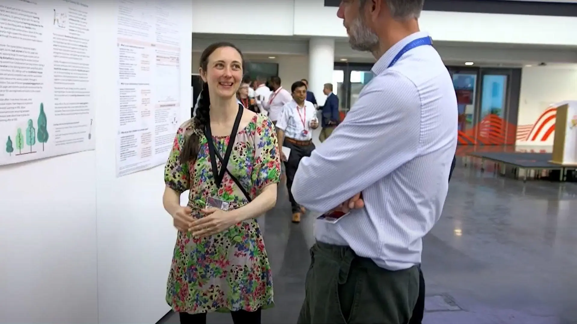 Image shows two people at the SLTR conference looking at a poster presentation