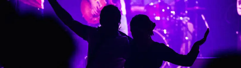 Silhouette of two concert-goers with the band in the background