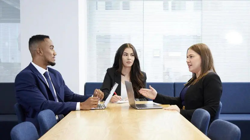 Image of three people working at a desk in a corporate environment