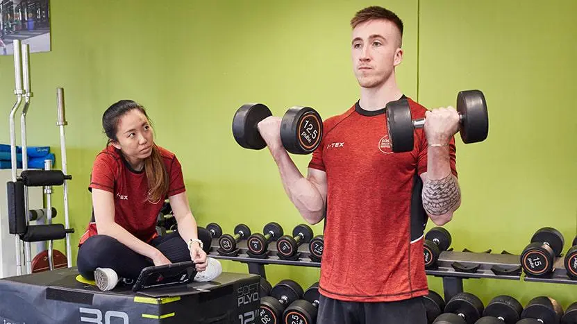 A health professional teaching a person in the gym