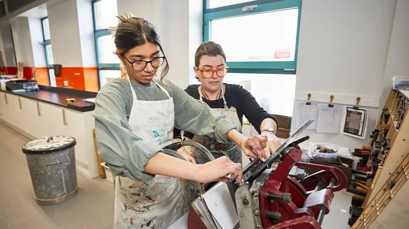 Two people working on a printing press