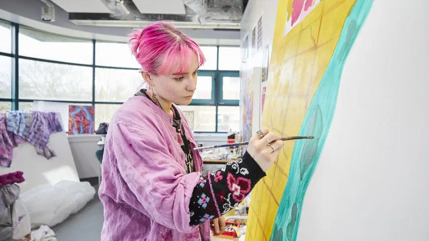 A female student with pink hair painting