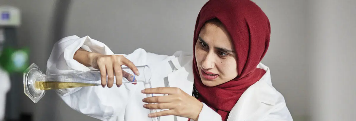 A biomedical science student pouring liquid into a test tube