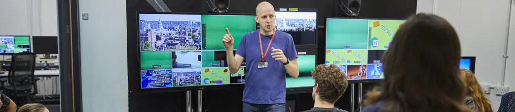 A media technology technician with students in an editing suite